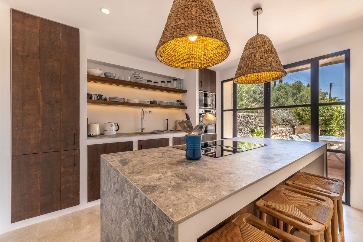 A kitchen with a large island and wicker lamps