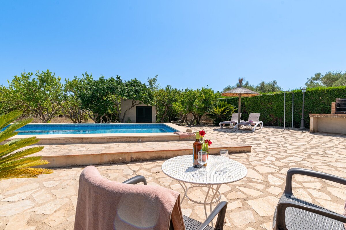 A bottle of wine sits on a table in front of a pool