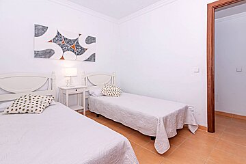 A bedroom with two beds and a painting on the wall