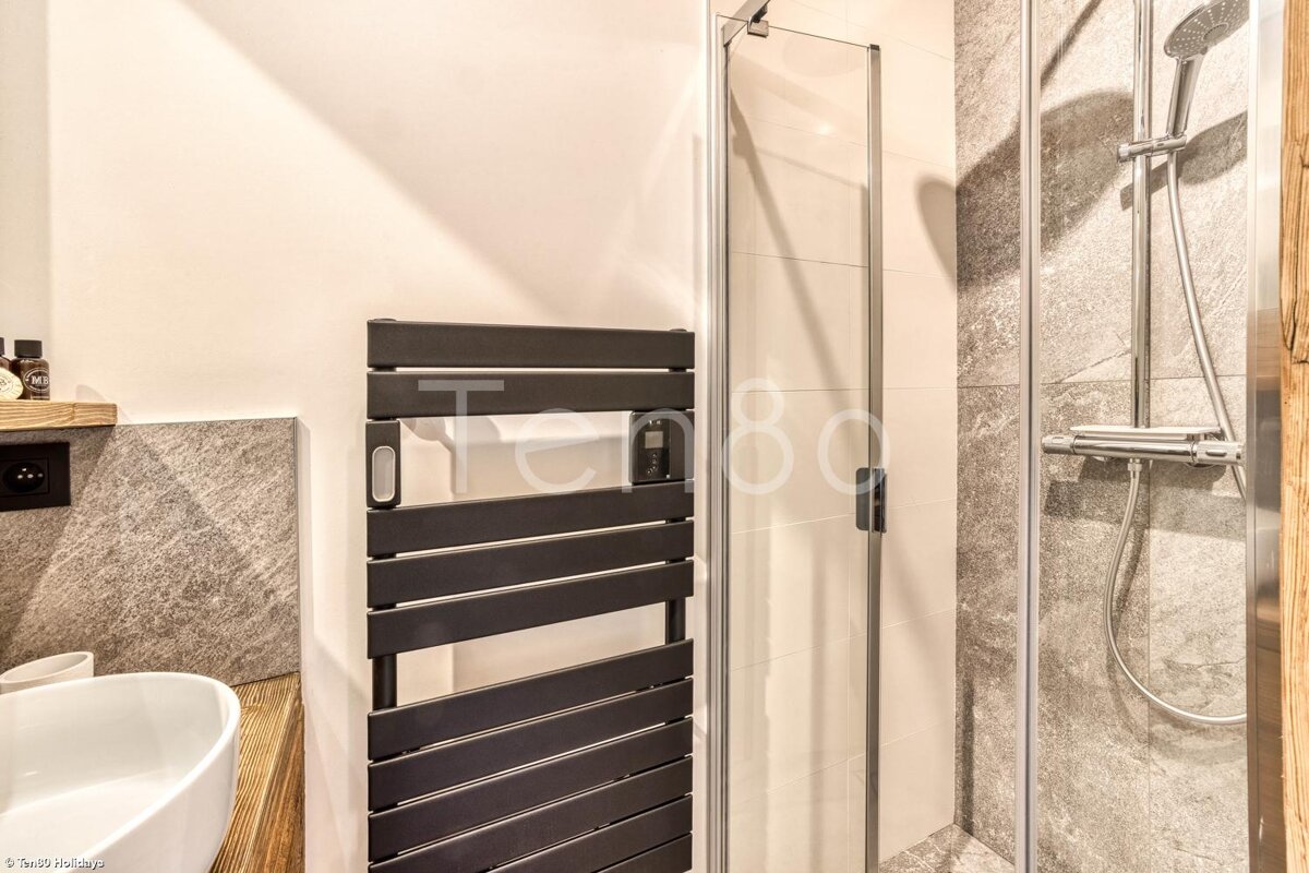 A bathroom with a towel rack and a shower with the word ten80 on the wall