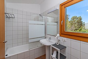 A bathroom with a sink and a window with trees in the background