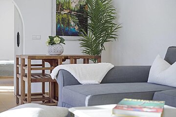 A living room with a couch and a table with a vase of flowers on it