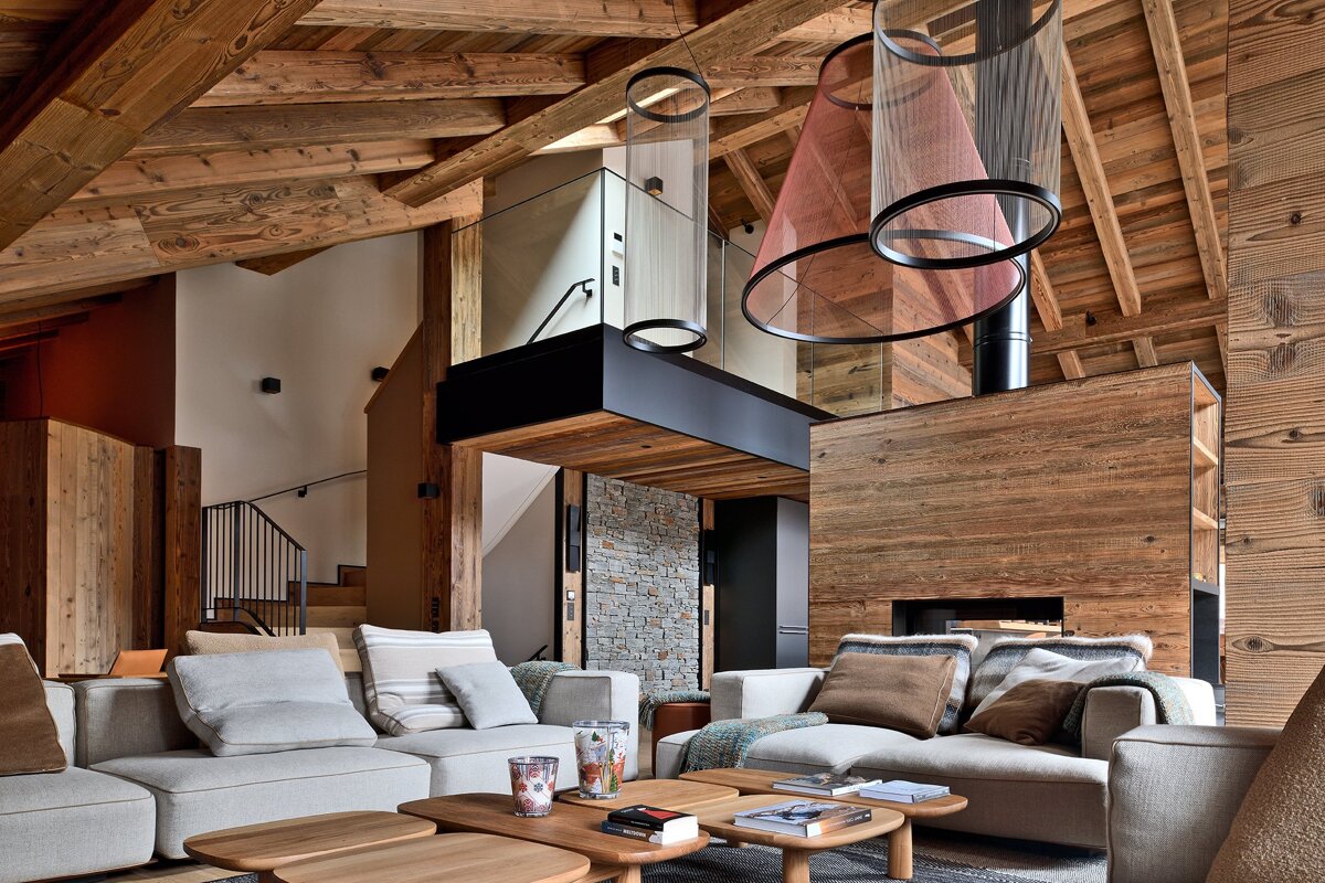 Cozy, modern chalet living room featuring vaulted wooden ceilings, comfortable sofas, and unique mesh pendant lights.