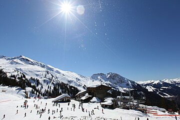 The sun is shining brightly over the snowy mountains