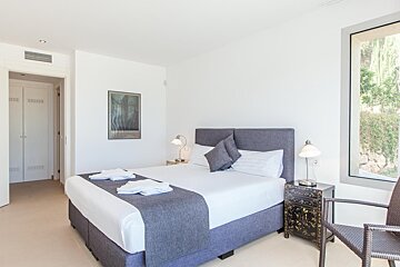 A bedroom with a large bed and a picture on the wall