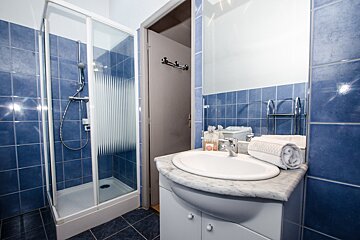 A bathroom with blue tiles and a sink and shower