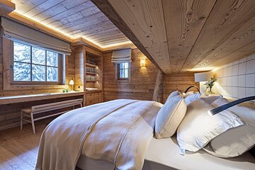 A wooden bedroom with a bed and a desk