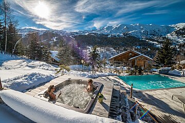 Two people in a hot tub with mountains in the background