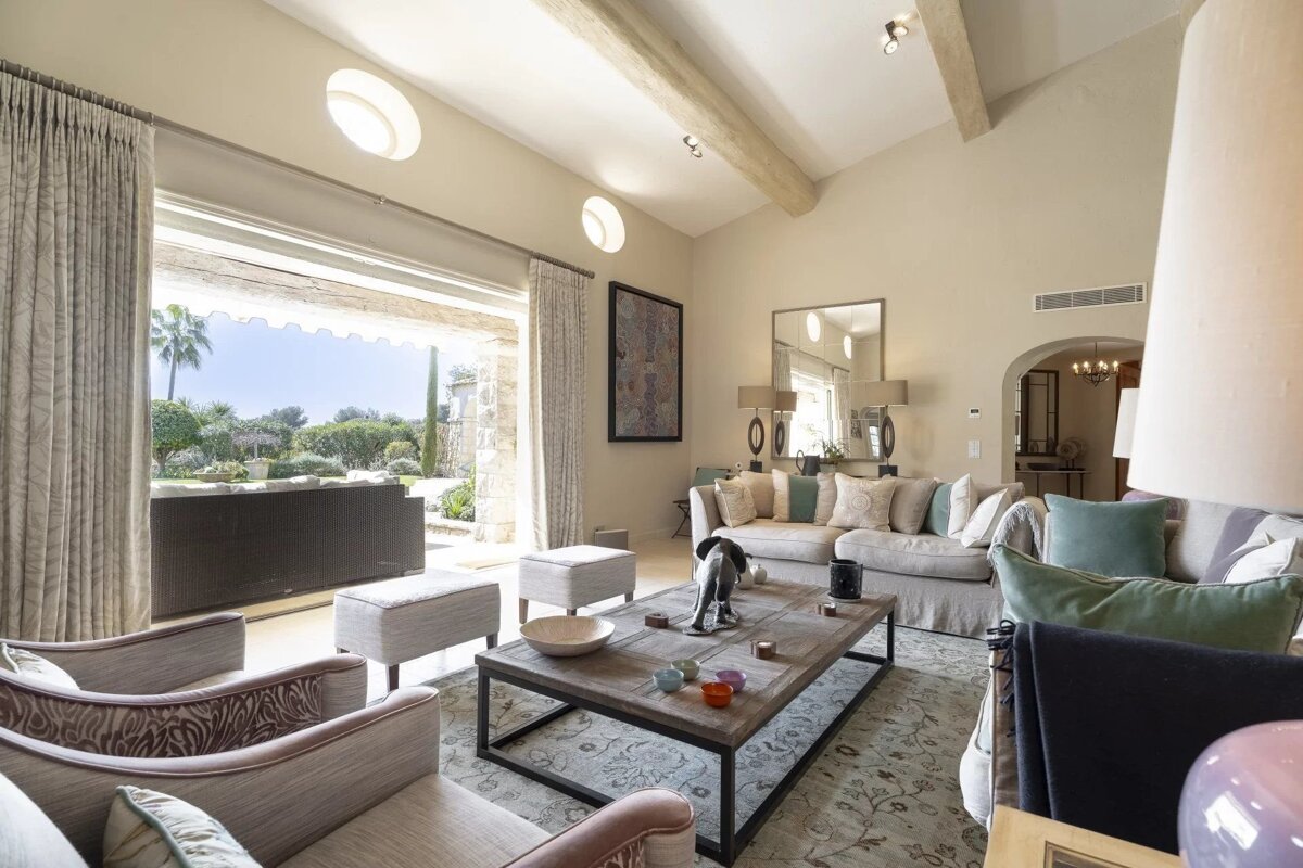Bright, elegant living room featuring comfortable sofas, a wooden coffee table, and large sliding doors opening to a scenic garden patio.