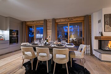 A dining room table with a bottle of wine on it