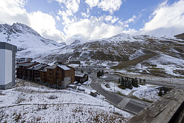A snowy mountain landscape with a few buildings in the foreground