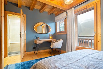 A bedroom with a bed and a desk with a mirror