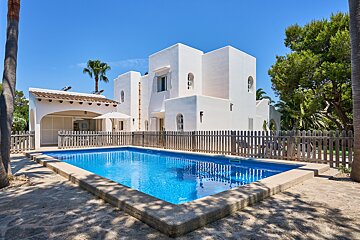 A large white house with a pool in front of it