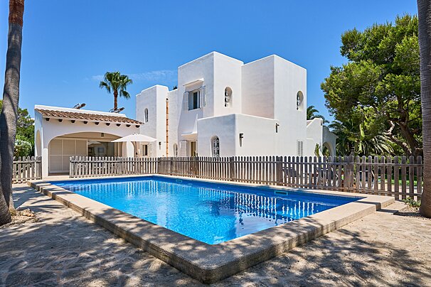 A large white house with a pool in front of it