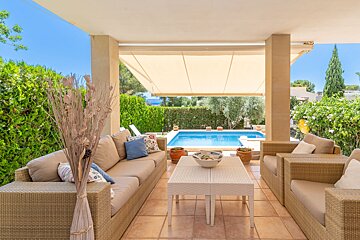 A patio with wicker furniture and a swimming pool in the background