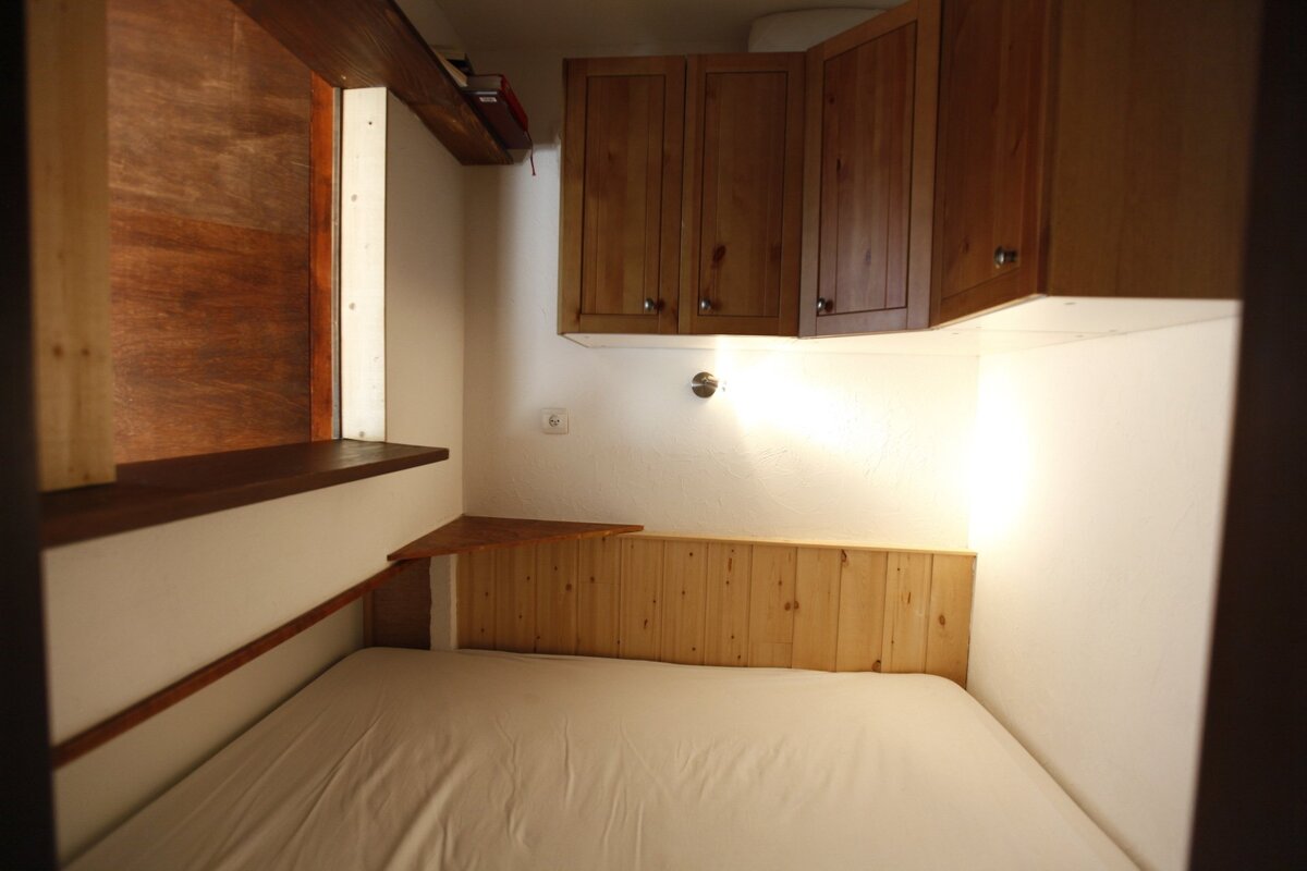 A small bedroom with a bed and wooden cabinets