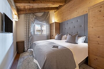 A bedroom with a bed and a television on the wall