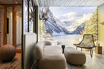 Chic room with modern seating facing a huge mural of a serene, snow-covered mountain lake and peaks, with pine trees and eagle decor.