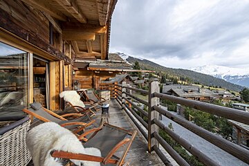 A balcony with chairs and a view of the mountains