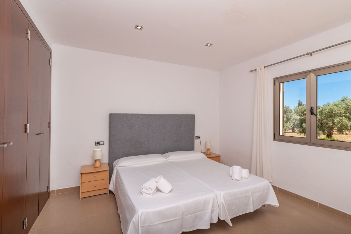 A bedroom with two beds and a window with trees in the background