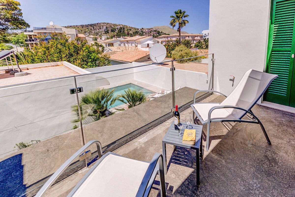 A balcony with two chairs and a table with a bottle of wine on it