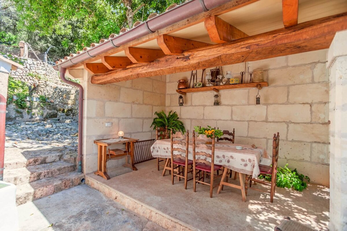 A patio with a table and chairs under a wooden roof