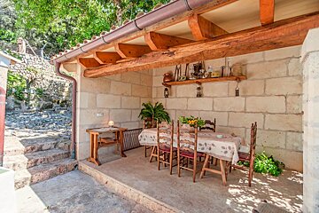 A patio with a table and chairs under a wooden roof