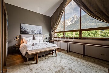 A bedroom with a large window looking out to the mountains