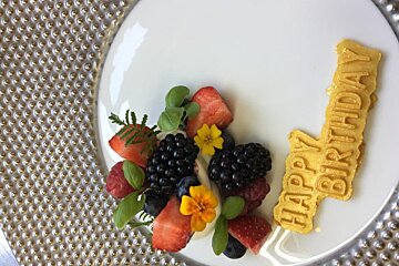 A white plate with berries and a sign that says happy birthday