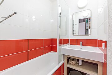 A bathroom with red and white tiles and a sink
