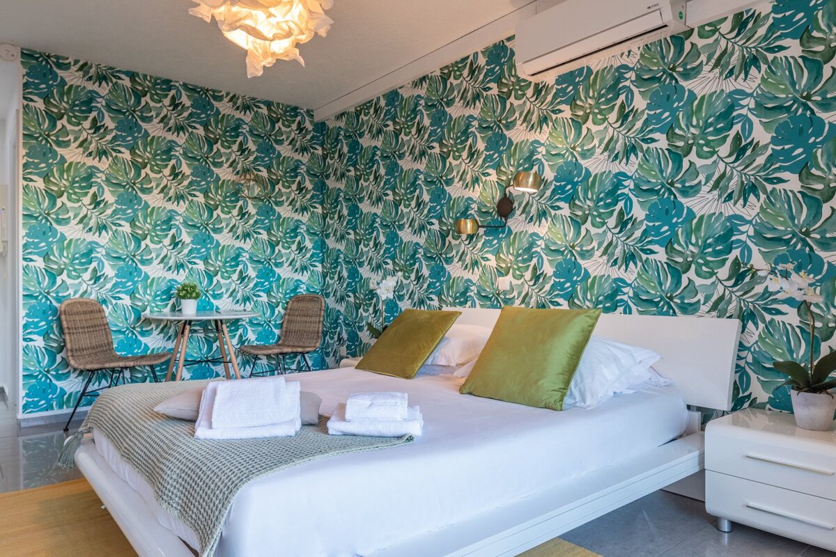 A bedroom with a white bed and green pillows