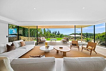 A living room with a view of a lush green field