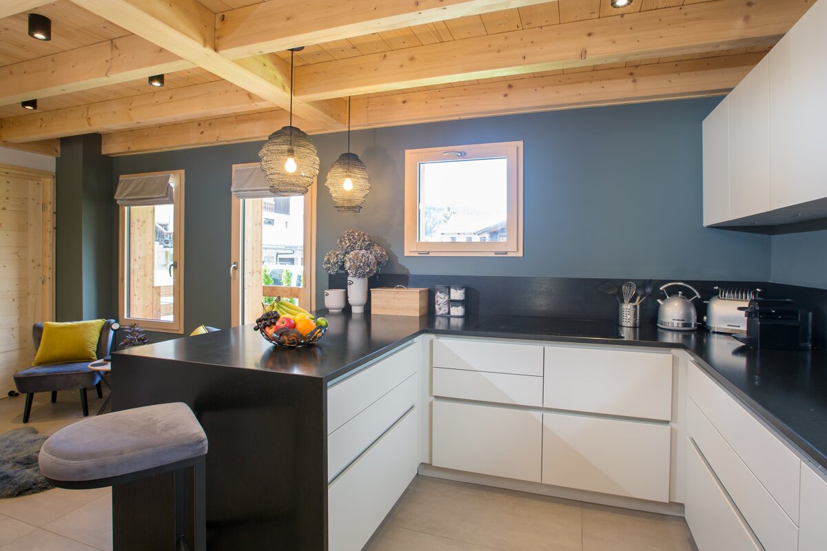 A kitchen with white cabinets and a black counter top