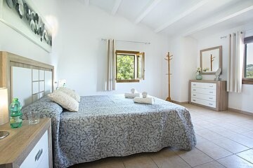 A bedroom with a large bed and a dresser
