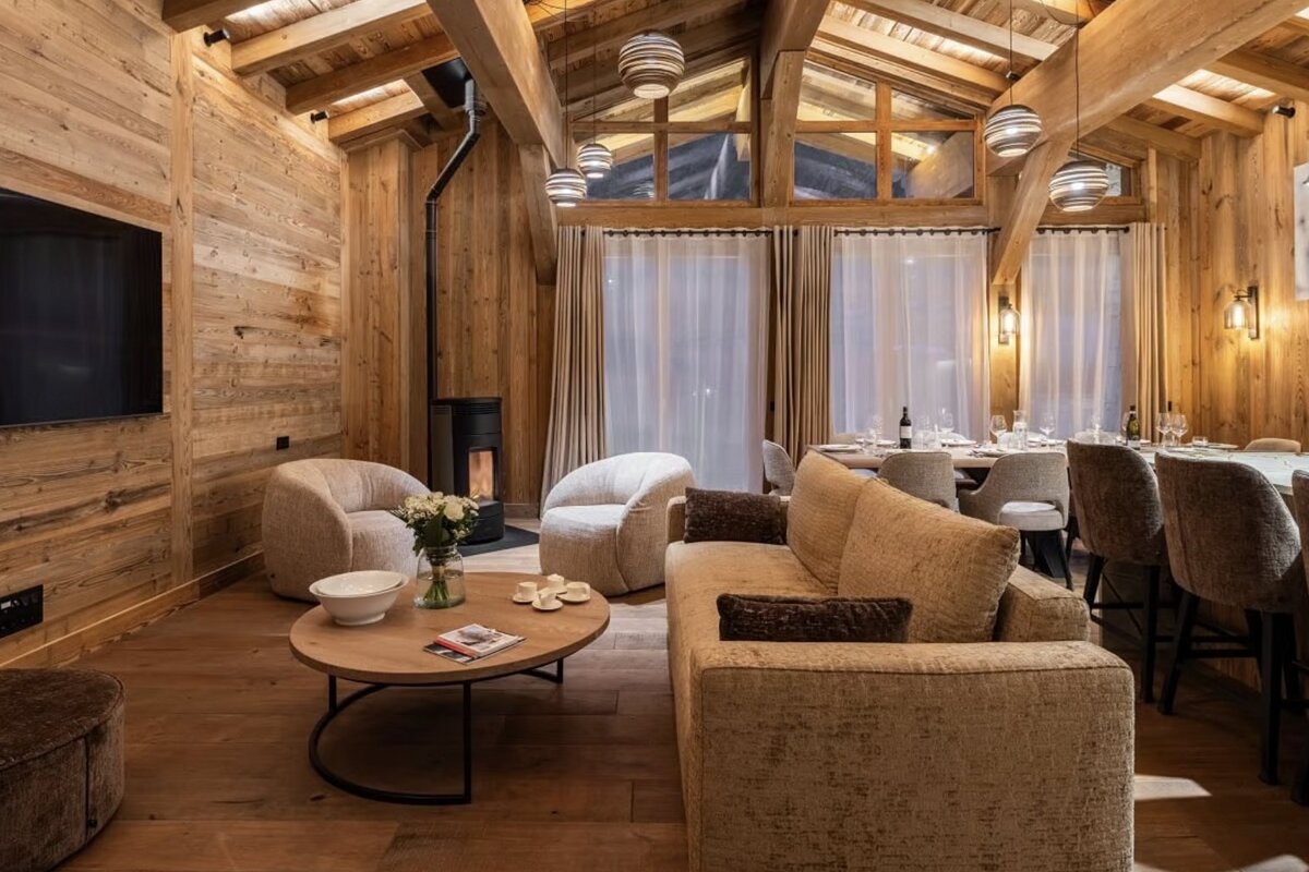 Cozy wood-paneled chalet interior with a modern living room, dining area, and fireplace. Rustic yet elegant design.