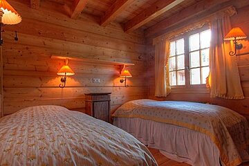 A bedroom with two beds and two lamps on the wall