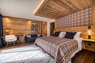 A bedroom with a plaid blanket on the bed