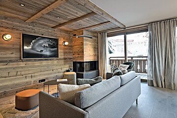 A living room with a couch and a television on the wall