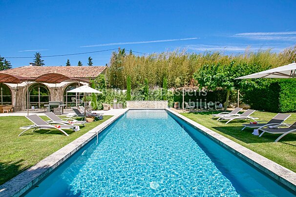 A large swimming pool surrounded by lawn chairs and umbrellas with the word immobilier on the bottom