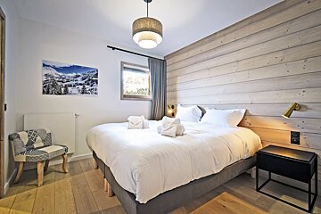 A bedroom with a large bed and a chair