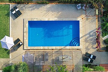 An aerial view of a large swimming pool surrounded by chairs and umbrellas