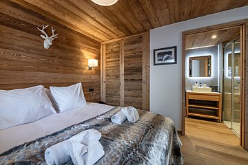 A bedroom with a deer head on the wall above the bed