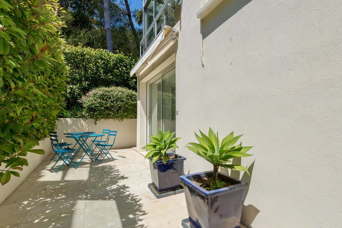 A patio with a table and chairs and potted plants