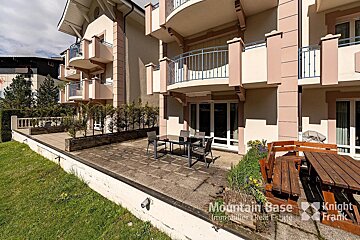 A patio with a table and chairs in front of a building that says mountain base