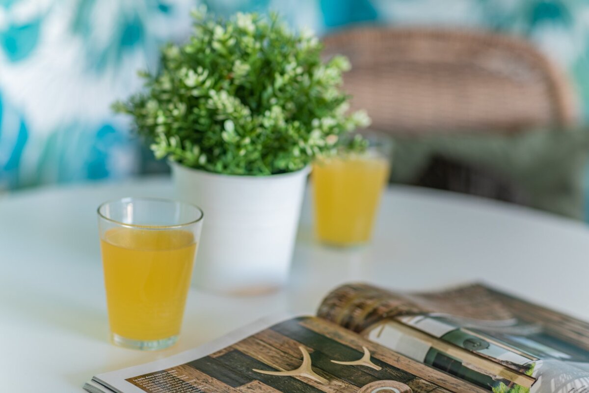 Two glasses of orange juice sit on a table next to an open magazine