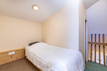 A bedroom with a single bed and a wooden railing