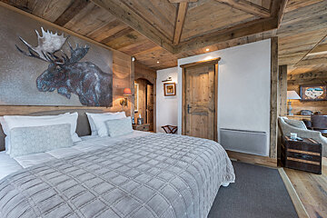 A bedroom with a moose painting above the bed
