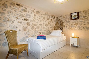 A bedroom with a stone wall and a single bed