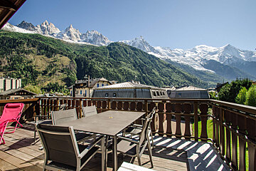 A table and chairs on a balcony with mountains in the background