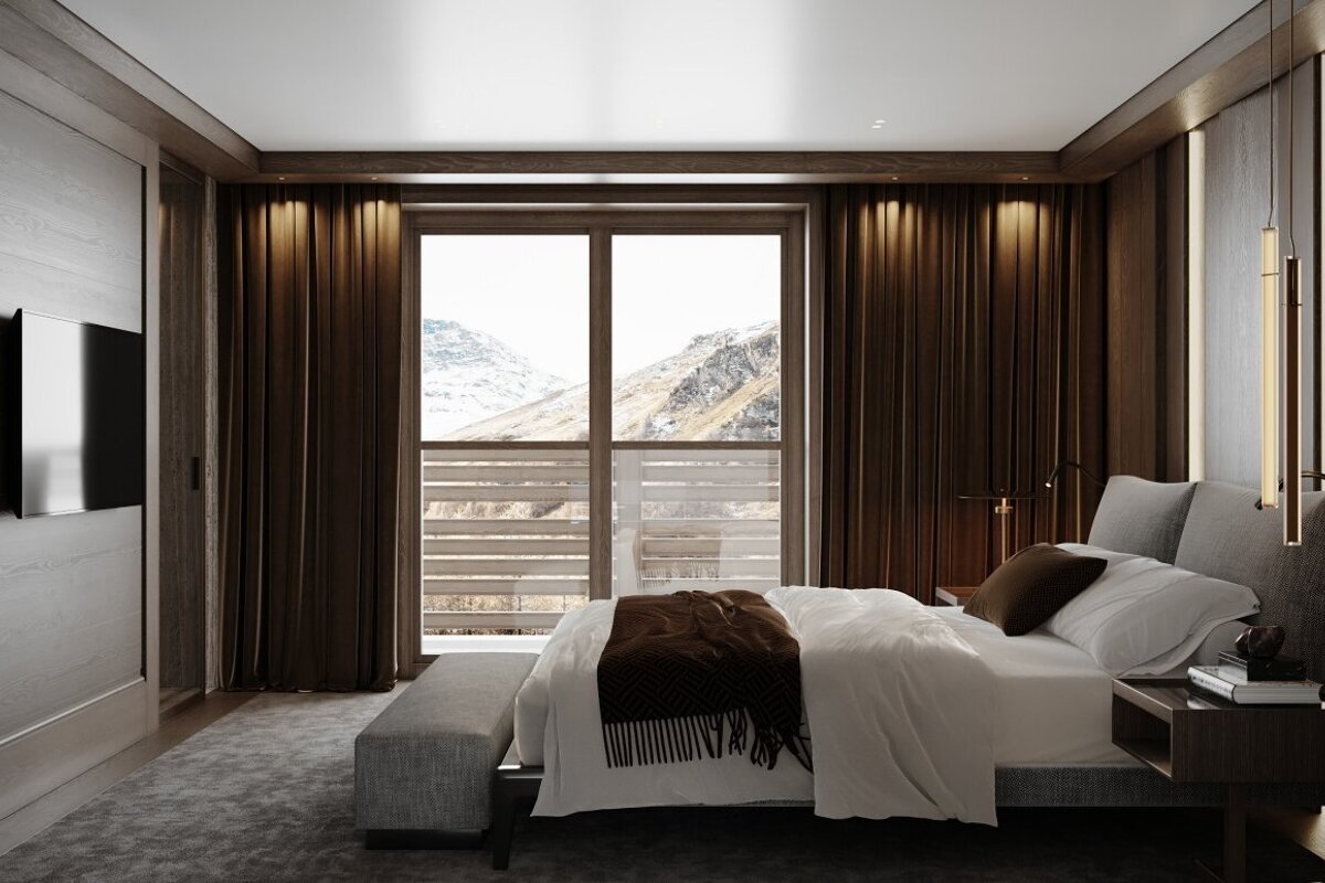 A stylish bedroom with dark wood accents, white bedding, and a large window overlooking a scenic, snowy mountain range.